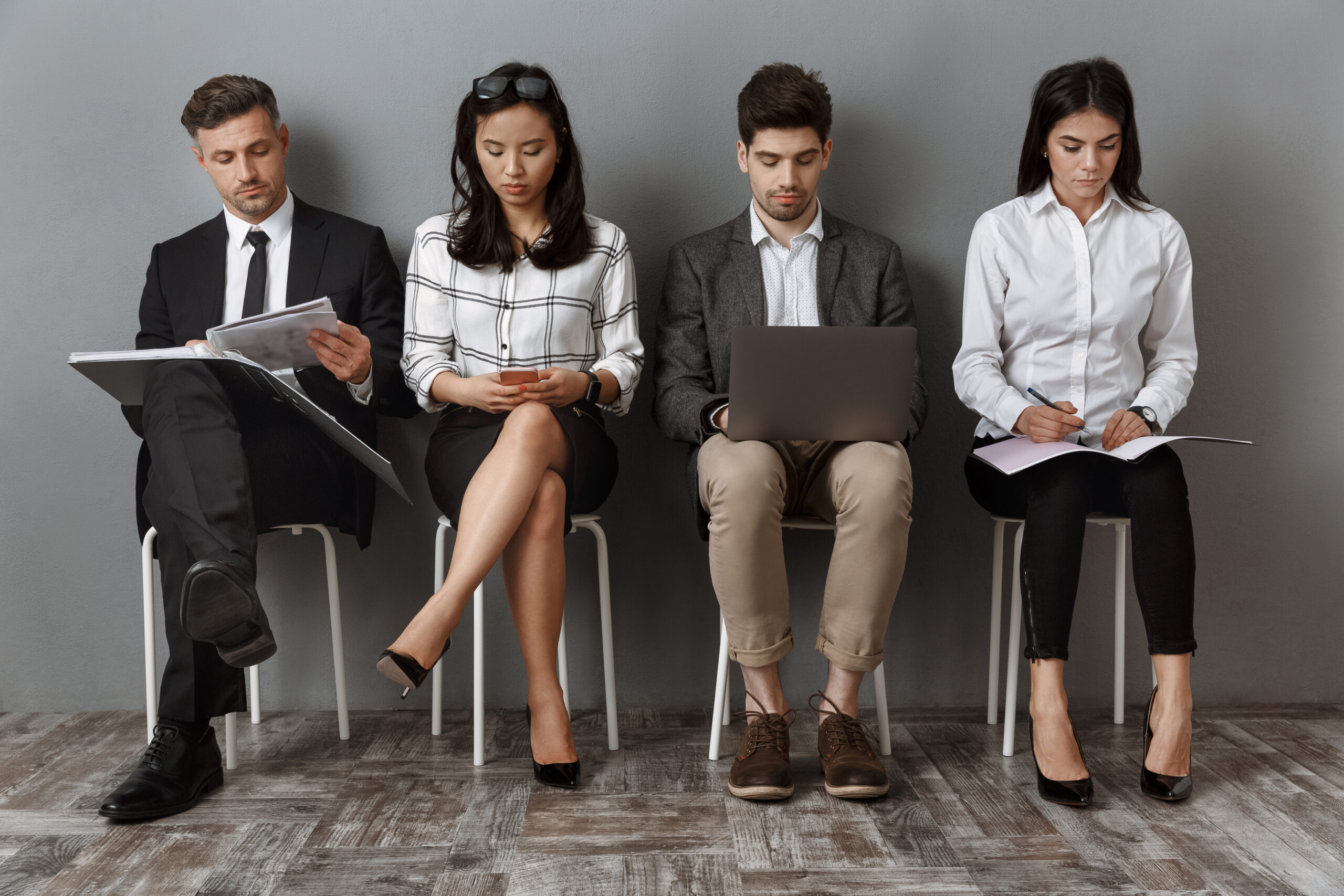 Applicants sitting in a row, waiting for interviews for good entry-level jobs.